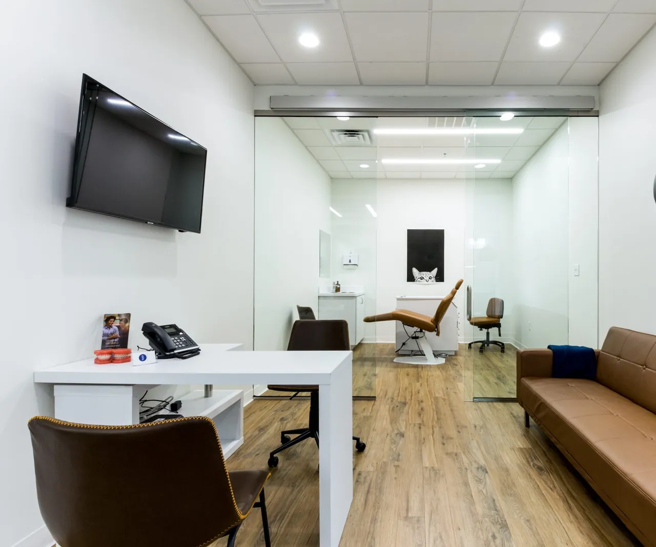 Kuspis kliniği: aydınlık bekleme alanı ve cam bölmenin ardında tedavi odası